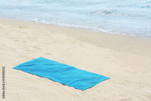 Blue towel on sandy beach near sea, space for text © New Africa