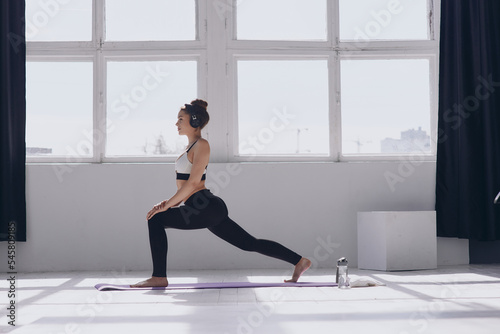 Beautiful young woman doing stretching exercises while practicing in front of the window