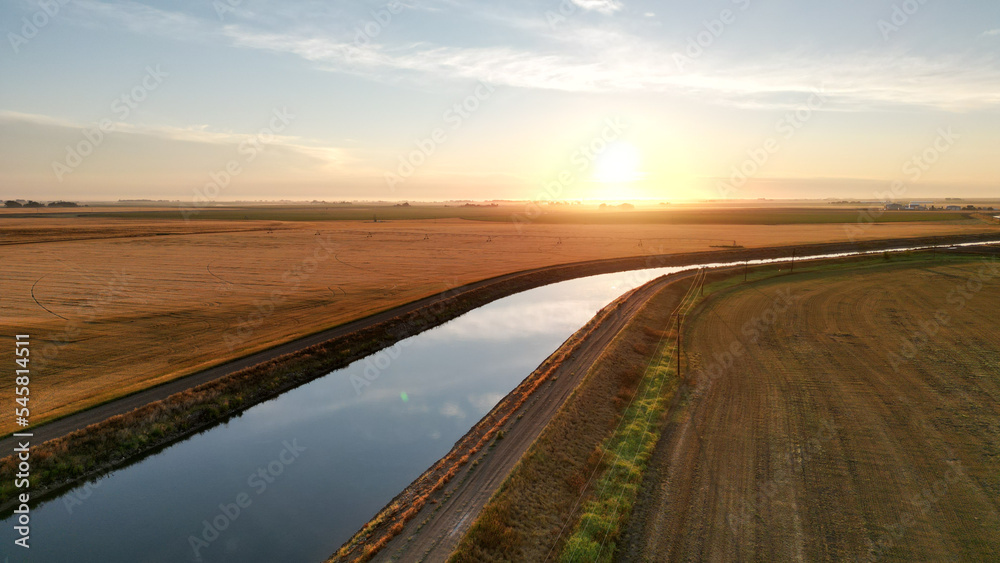 Drone view during sunrise over a farm hay field and river in Alberta Canada