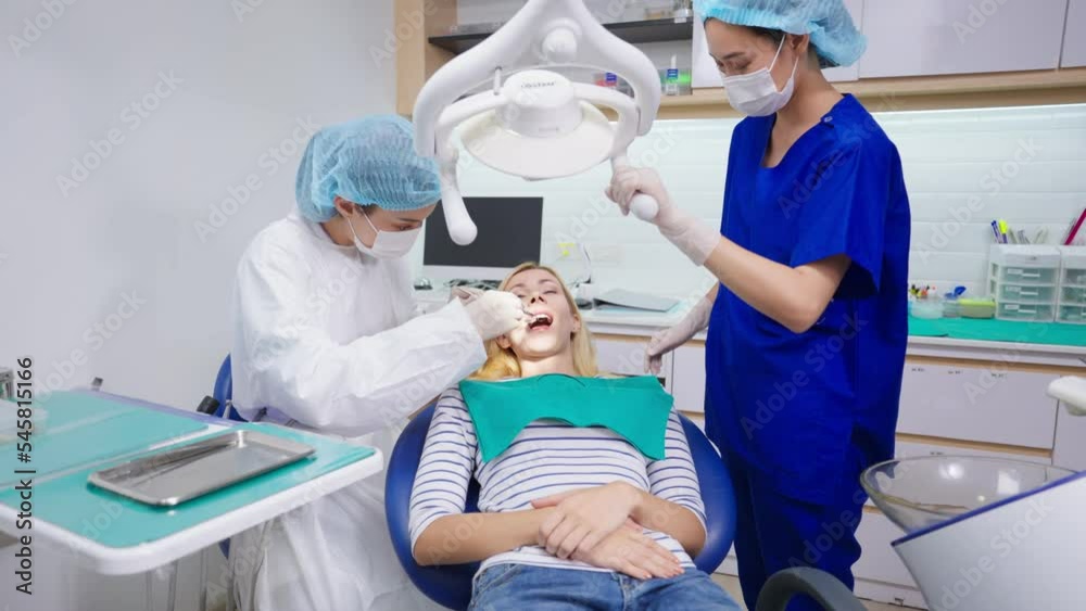 Female dentist examine tooth to Caucasian girl at dental health clinic.