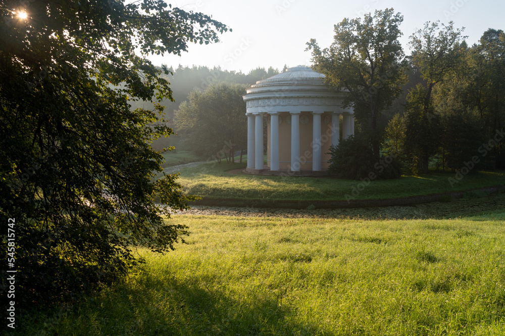 View of the Temple of Friendship on the bank of the Slavyanka River in the Pavlovsky Palace and Park Complex on an foggy summer morning, St. Petersburg, Russia