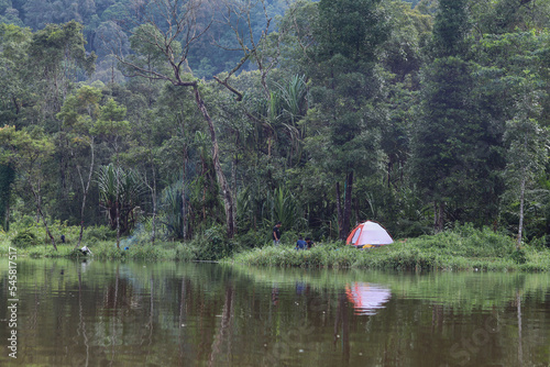 camping visitors use tents by the lake surrounded by tropical forests
