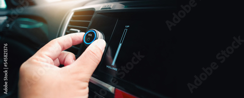 Fotografie The driver hand is turning up or down the volume of the car music player or radi