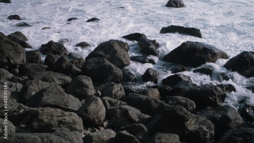 The rocks on the coastline get submerged by a wave The rocks on the coastline get submerged by a wave