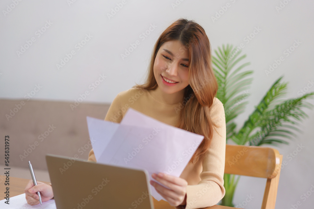 Business at home concept, Businesswoman is reading data on document and laptop while taking notes Business at home concept, Businesswoman is reading data on document and laptop while taking notes