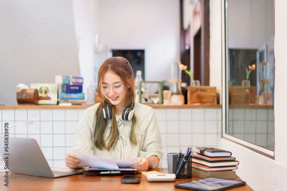 Remote work concept, Woman entrepreneur reading document and working on laptop in coworking space Remote work concept, Woman entrepreneur reading document and working on laptop in coworking space