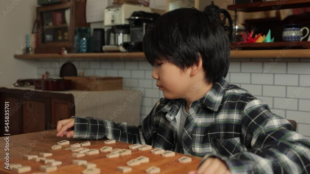 Japanese boy playing Shogi, Japanese chess, at home. Japanese boy playing Shogi, Japanese chess, at home.