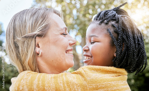 Hug, smile and mother love with girl in a nature park with love, foster care and diversity. Happy, relax and hugging mom and adopted kid bonding together in summer on mothers day or holiday outdoor photo