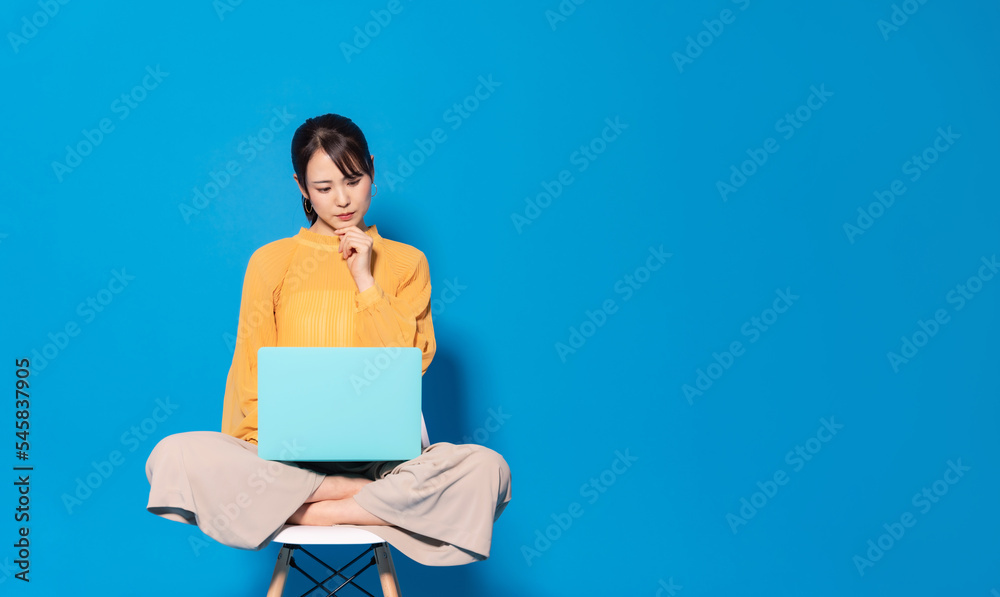 ノートパソコンを見ながら考える女性