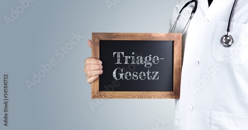 Triage-Gesetz. Arzt zeigt Begriff auf einem Holz Schild. Handschrift auf Tafel photo
