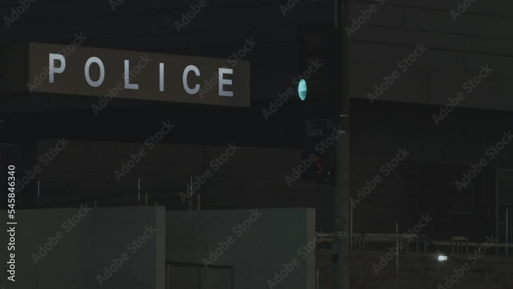 White Glowing sign board of Police station at night with traffic signal blinking for low car traffic White Glowing sign board of Police station at night with traffic signal blinking for low car traffic