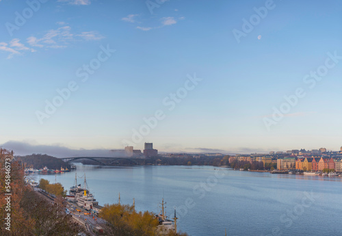 Panorama, the bay Riddarfjärden with piers in the districts Norr and Söder Mälarstrand, long bridge and skyscrapers office buildings a foggy rising and sunny autumn day in Stockholm