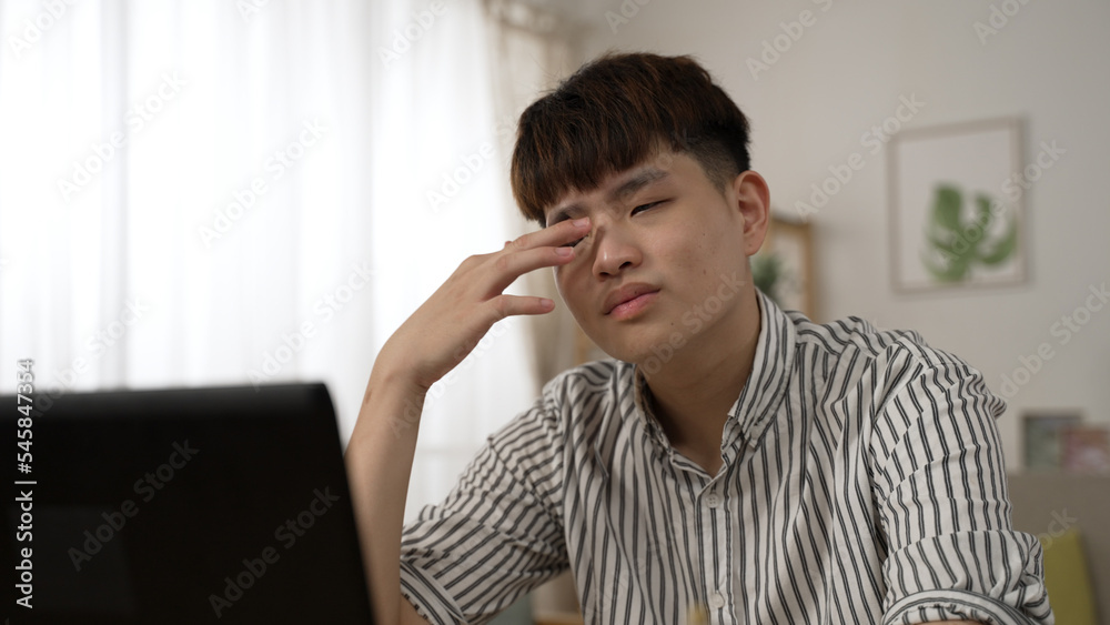 tired asian businessman suffering a blurred vision is still having trouble seeing clearly after massaging his eyes while working from home on the computer. tired asian businessman suffering a blurred vision is still having trouble seeing clearly after massaging his eyes while working from home on the computer.