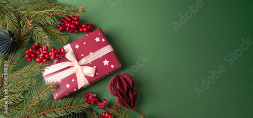 Banner with Christmas gift and Christmas tree branches on green background.Flat lay, top view, copy space
