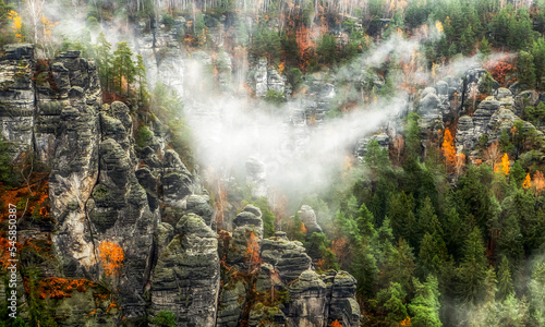 Quadro su tela Misty weather in colorful autumn forest and rock formations