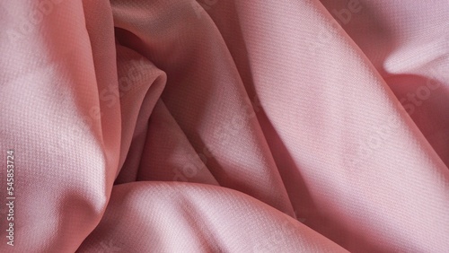 Red silk background. The texture of the pink polycotton fabric is smooth and soft with beautiful close-up fabric details. Textile pattern with dense, breathable and flexible fibers.