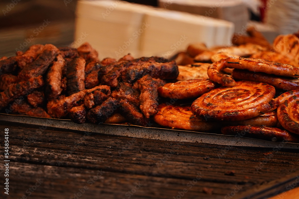 Meat and sausages on the grill. Prepared from meat with a delicious taste. Appetizing sausages. Detail photo. Meat and sausages on the grill. Prepared from meat with a delicious taste. Appetizing sausages. Detail photo.