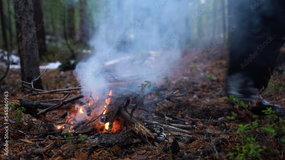 Young bearded man kindles a fire. Campfire in the forest. Beautiful landscape of nature and trees. Sparks and flames. Rest by the fire. Camping in the woods. Burning firewood. Evening bonfire. Young bearded man kindles a fire. Campfire in the forest. Beautiful landscape of nature and trees. Sparks and flames. Rest by the fire. Camping in the woods. Burning firewood. Evening bonfire.