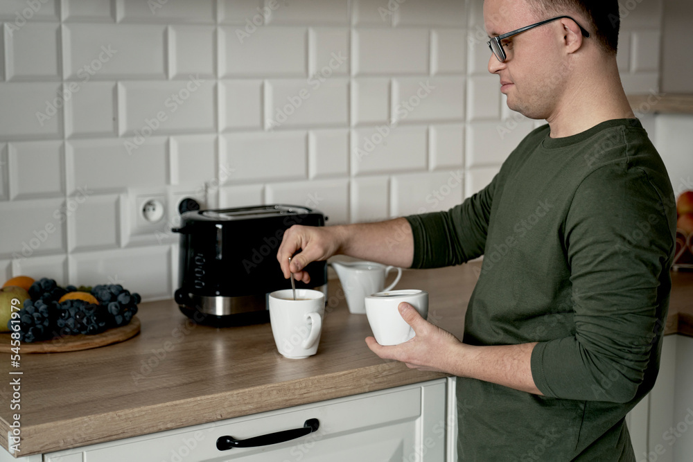 Caucasian man with down syndrome preparing coffee in the kitchen
