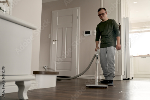 Caucasian man with down syndrome vacuuming at home