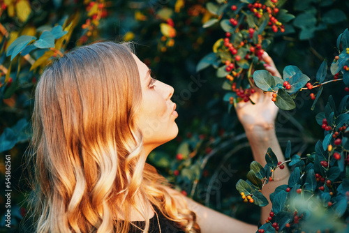 Beautiful face of a young woman against the background of a bush of berries. Outdoor portrait