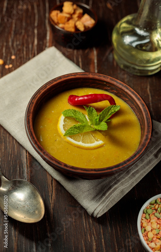 Turkish soup of chickpeas and lentils, with the addition of hot red pepper, lemon and mint. Close-up on a dark wooden background., vertical