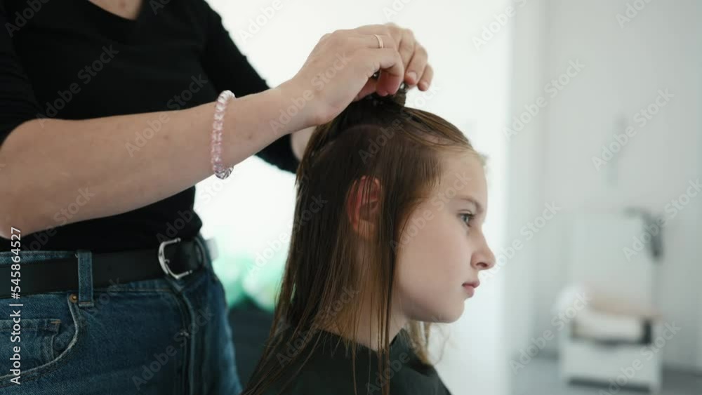 Hairdresser preparing hair of preteen girl for haircut. Female child in beauty salon Hairdresser preparing hair of preteen girl for haircut. Female child in beauty salon
