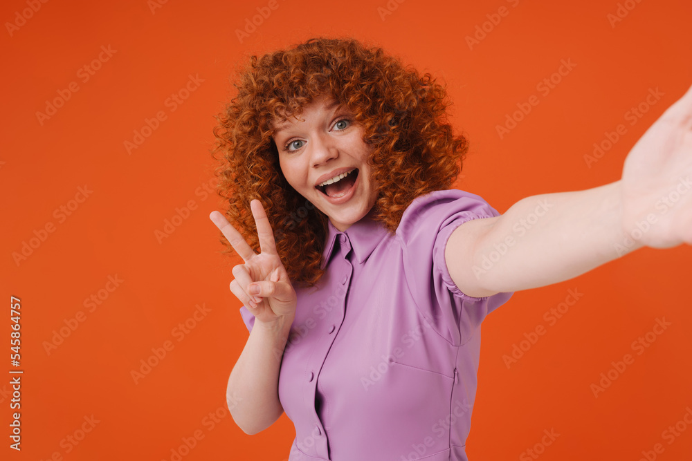 White ginger woman smiling and gesturing while taking selfie photo