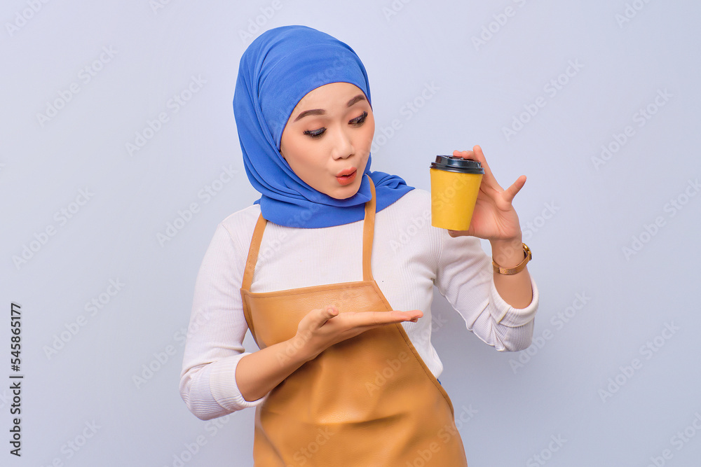 Cheerful pretty young barista girl in apron showing takeaway coffee cup isolated on white background Cheerful pretty young barista girl in apron showing takeaway coffee cup isolated on white background
