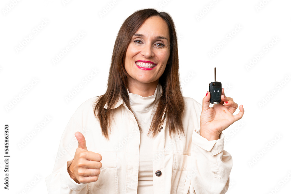 Middle-aged woman holding car keys over isolated background with thumbs up because something good has happened Middle-aged woman holding car keys over isolated background with thumbs up because something good has happened