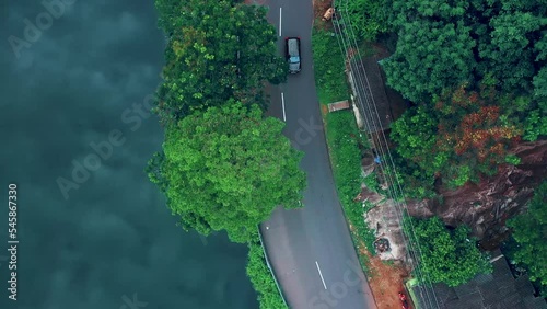Aerial view of car driving through the forest and the lake on the side. Beautiful mountain road. Driving on the mountain road. Road trip. Netta Sceneries Point
