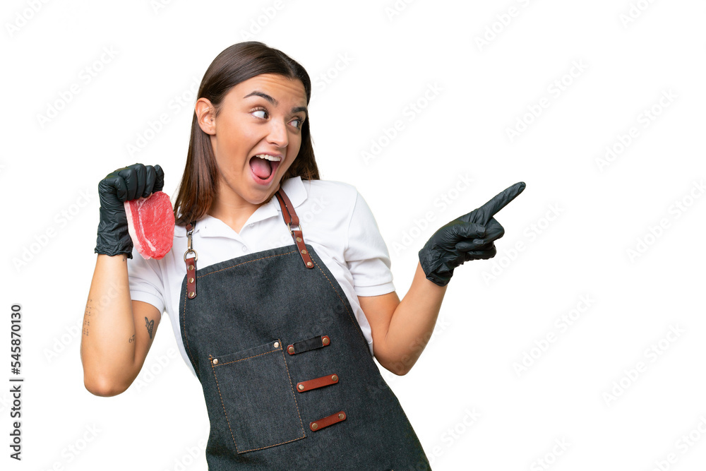 Butcher woman wearing an apron and serving fresh cut meat isolated on green chroma background pointing finger to the side and presenting a product Butcher woman wearing an apron and serving fresh cut meat isolated on green chroma background pointing finger to the side and presenting a product