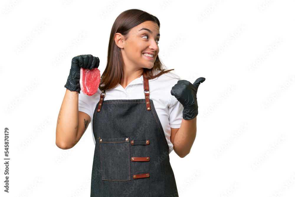 Butcher woman wearing an apron and serving fresh cut meat isolated on green chroma background pointing to the side to present a product Butcher woman wearing an apron and serving fresh cut meat isolated on green chroma background pointing to the side to present a product
