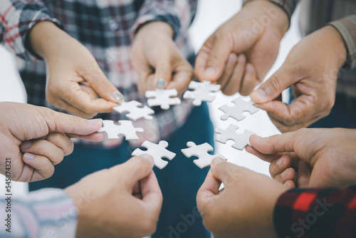 Concept of finding solution. close up people assembling jigsaw puzzles in work meeting Banner with happy office worker playing games during team building activity.