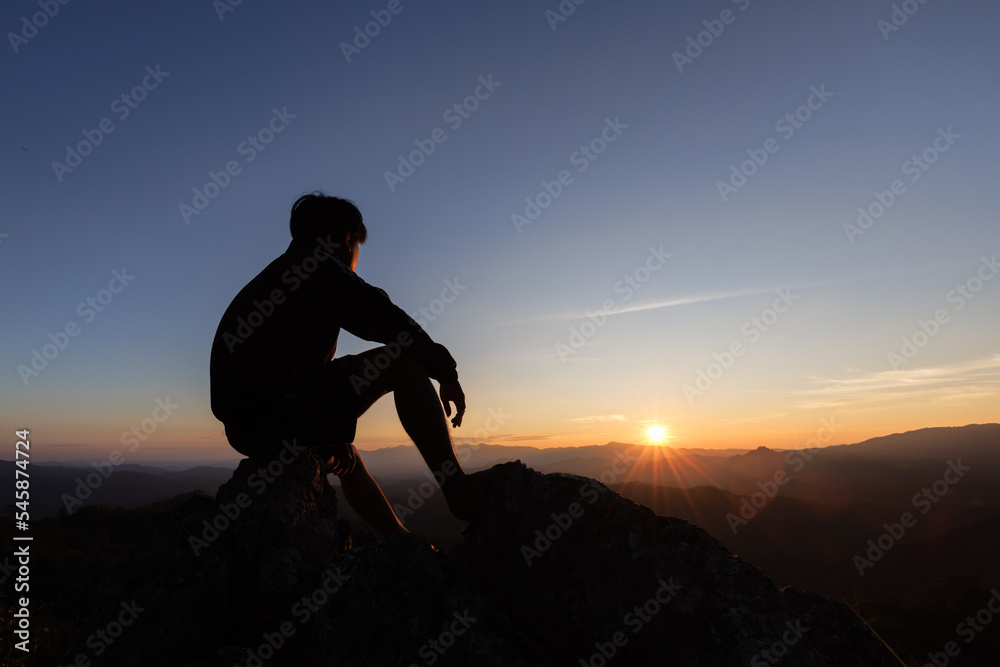 silhouette of Sad man sitting alone on top of a mountain at sunset, Depression and loneliness.  The concept of stress and gloom.