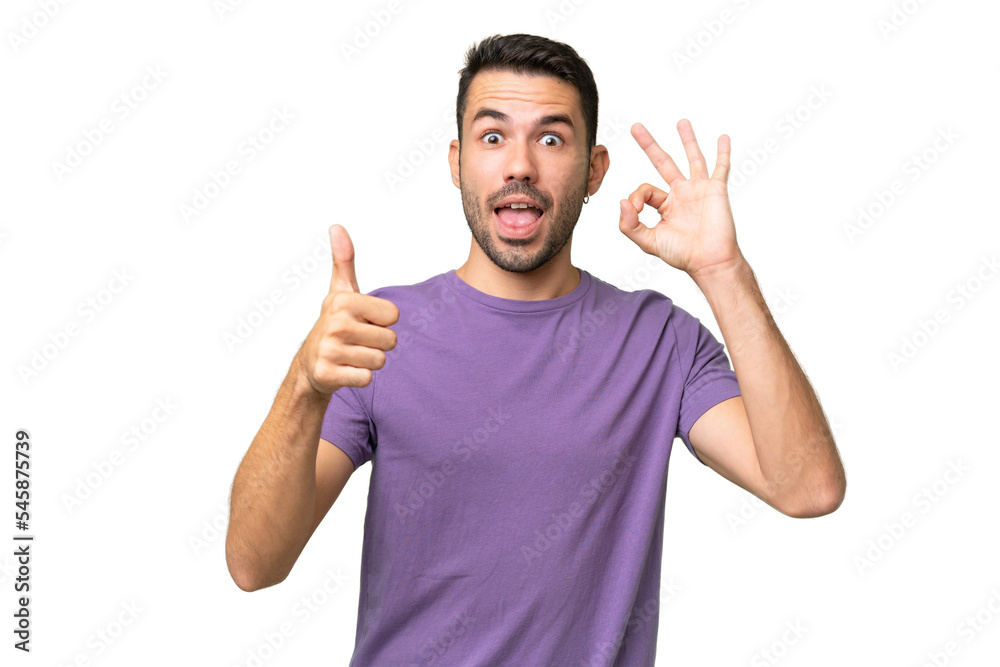 Young handsome caucasian man over isolated background showing ok sign and thumb up gesture Young handsome caucasian man over isolated background showing ok sign and thumb up gesture