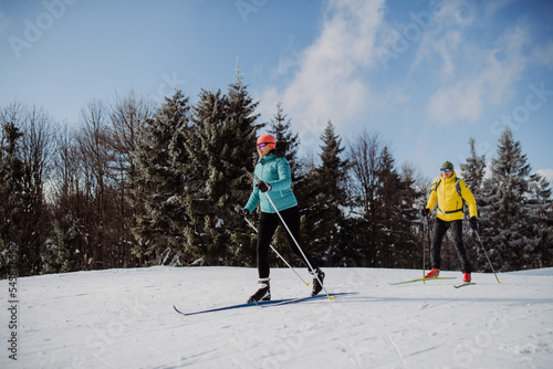 Senior couple skiing together in the middle of forest.