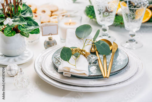 Christmas table setting with eucalyptus, cutlery and potted cyclamen in white and green tone