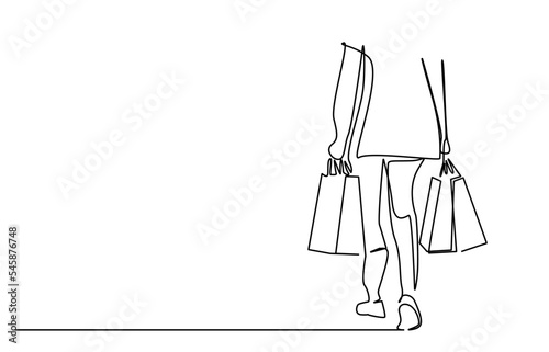 young person walking holding shopping bags in hands back view