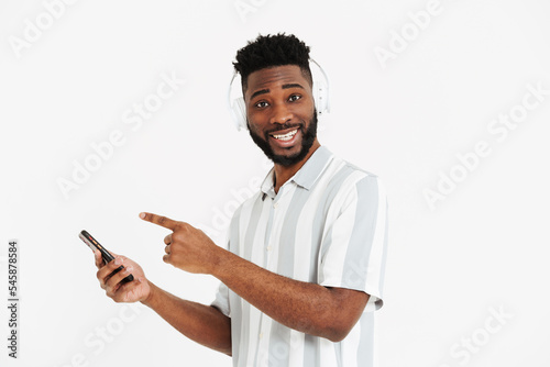 Black man in headphones holding and pointing finger at cellphone © Drobot Dean