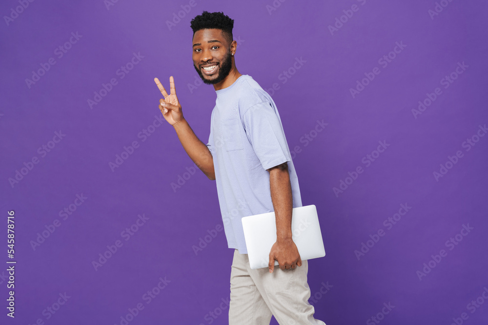 Happy african american man gesturing peace sign and carrying laptop Happy african american man gesturing peace sign and carrying laptop