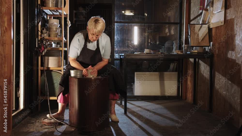 An old woman potter works with a clay in the studio An old woman potter works with a clay in the studio