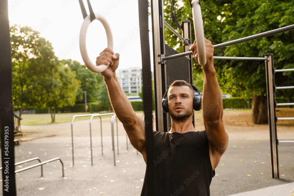 Young man listening to music with headphones during workout in park