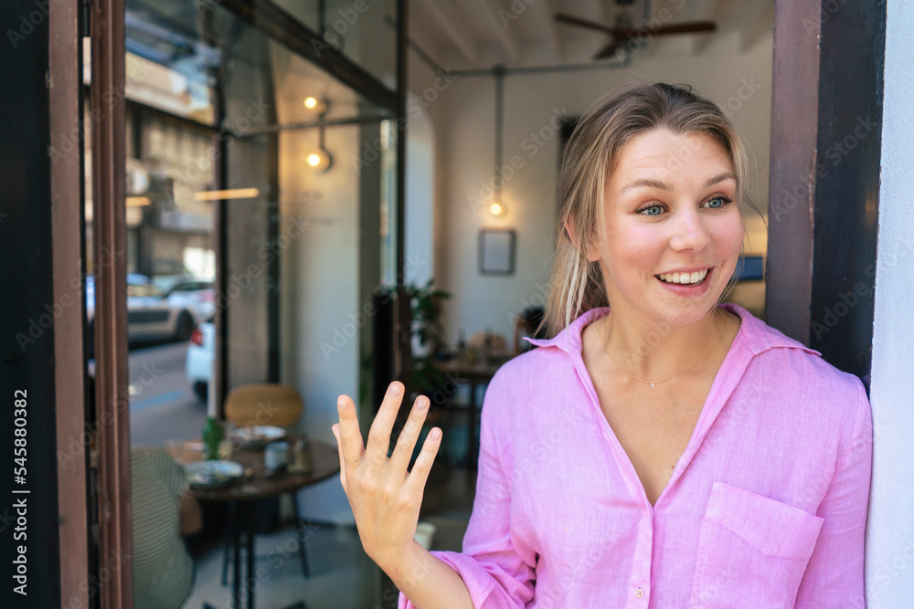 Happy businesswoman gesturing and talking at doorway in cafe Happy businesswoman gesturing and talking at doorway in cafe
