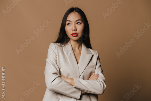 Young woman wearing jacket posing with arms crossed and looking aside
