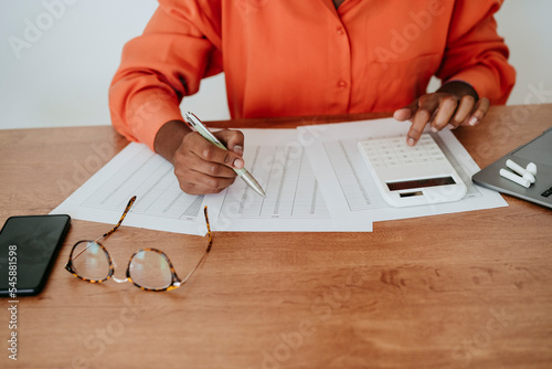 Businesswoman calculating financial bills at desk