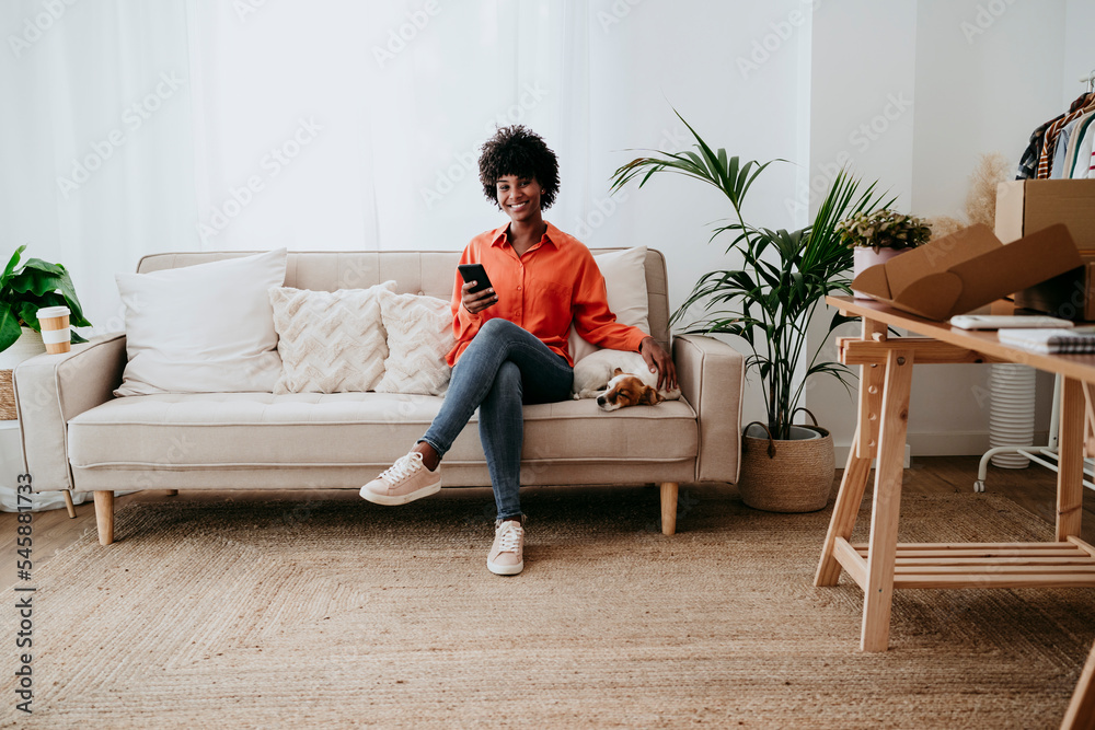 Smiling freelancer sitting with dog on sofa at home office Smiling freelancer sitting with dog on sofa at home office