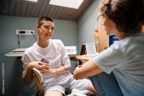 Young white women smiling and talking together while sitting at desk