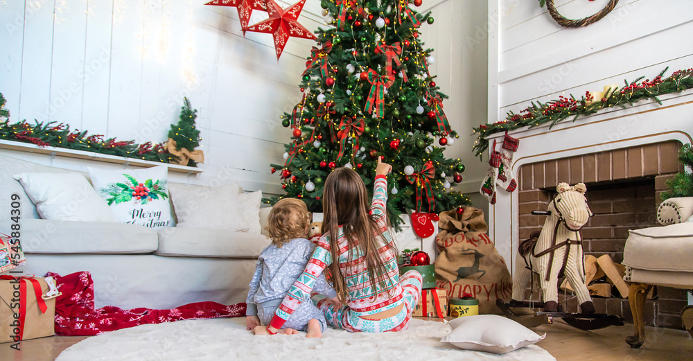 Children look at the Christmas tree. Selective focus. Children look at the Christmas tree. Selective focus.