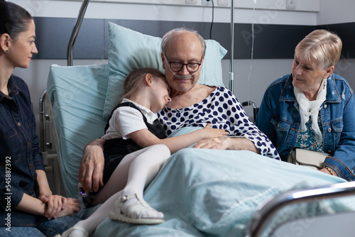 Elderly man in geriatric clinic bedroom hugging little girl Fototapet